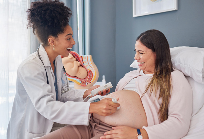 Obstetrician examining a pregnant woman's abdomen using a handheld ultrasound device
